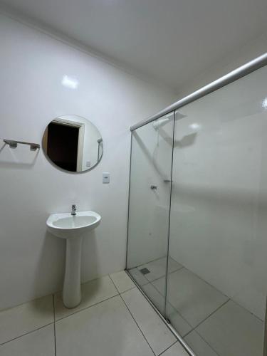 a bathroom with a sink and a mirror and a shower at Novo Hotel Uirapuru in Araraquara