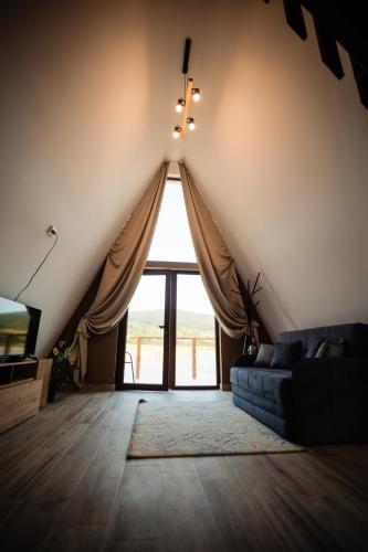 a living room with a couch and a large window at Lagos Lac de Pescuit in Boiştea-Boerească