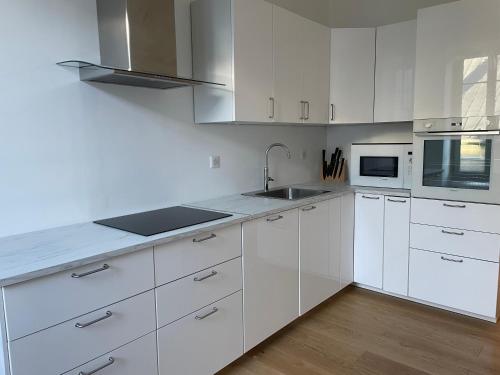 une cuisine blanche avec des armoires blanches et un évier dans l'établissement Superbe maison de vacances au centre d’embrun, à Embrun