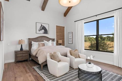 een slaapkamer met een bed en twee stoelen en een raam bij Calivence Haus - Estate Home in Fredericksburg