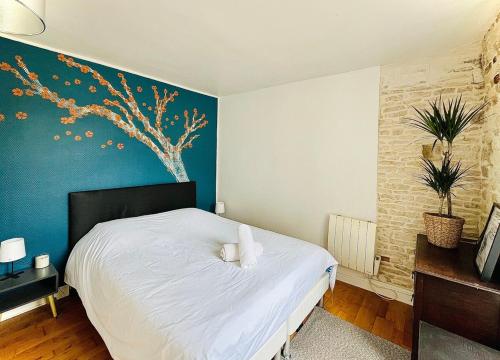 une chambre avec un lit blanc avec un mur bleu dans l'établissement Le charmant Caponière, à Caen