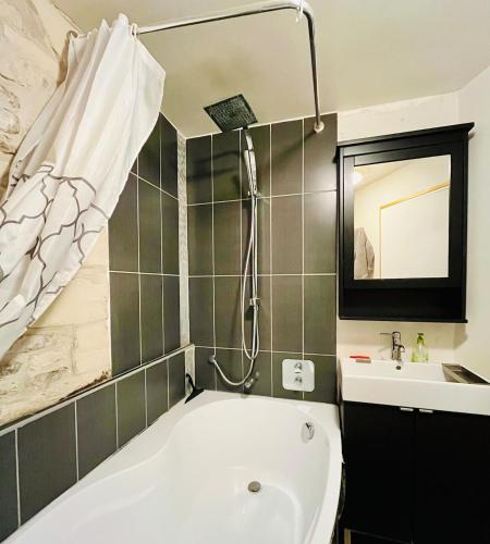 une salle de bain avec une baignoire et un lavabo dans l'établissement Le charmant Caponière, à Caen