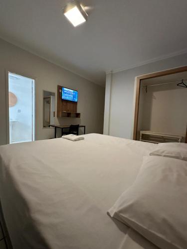 a large white bed in a room with a television at Novo Hotel Uirapuru in Araraquara