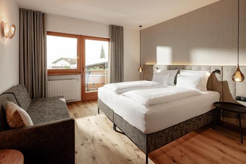 a bedroom with a large white bed and a couch at Panoramahotel Huberhof in Maranza