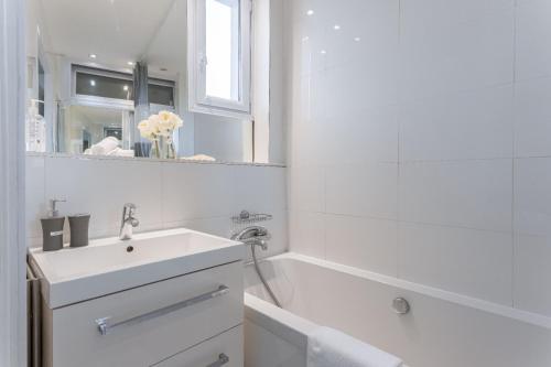 une salle de bain blanche avec un lavabo et une baignoire dans l'établissement Duplex Jaurès - city center, AC, 10mn from Palais, à Cannes
