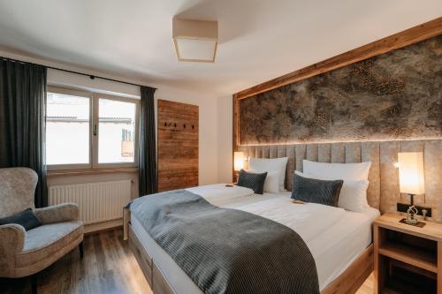 a bedroom with a large bed and a chair at Apartment Sella in Siusi