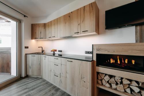a kitchen with wooden cabinets and a fireplace at Apartment Sella in Siusi