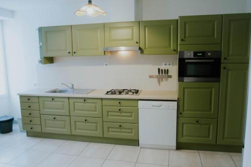 a kitchen with green cabinets and a stove top oven at Cozy house with garden, comfort for 6 people in Maulévrier