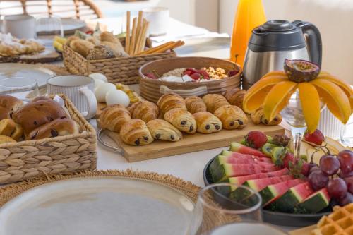 a table topped with baskets of pastries and fruit at Villa Eva By Milos Concierge in Adamas