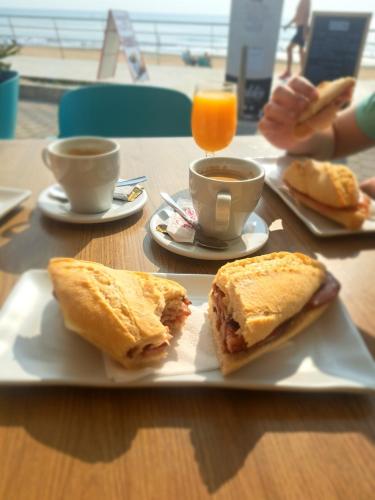 a table with a plate with sandwiches and cups of coffee at Paradiso de Playa LaMata in La Mata
