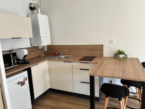 une cuisine avec des armoires blanches et un comptoir en bois dans l'établissement Studio - bord de mer, à Les Sables-dʼOlonne