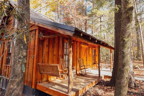 a cabin in the woods with a bench and a tree at Summer Breeze cabin at Cabin Fever in NC in Saluda