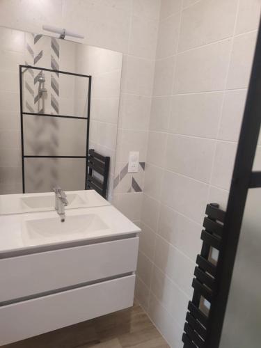 une salle de bain blanche avec un lavabo et un miroir dans l'établissement LOYAT - 3 chambres, 2 salles de bain, 1 terrasse, à Loyat
