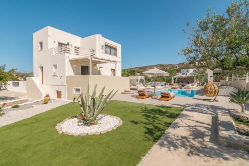 a large white house with a yard and a pool at Villa Eva By Milos Concierge in Adamas