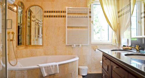 a bathroom with a tub and two sinks and a shower at Seehotel Porcia in Pörtschach am Wörthersee