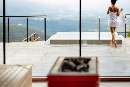 a woman in a white dress looking out of a window at Panoramahotel Huberhof in Maranza