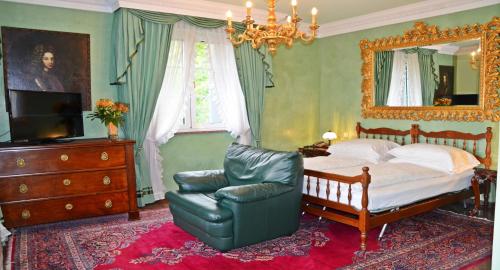 a bedroom with a bed and a chair and a mirror at Seehotel Porcia in Pörtschach am Wörthersee