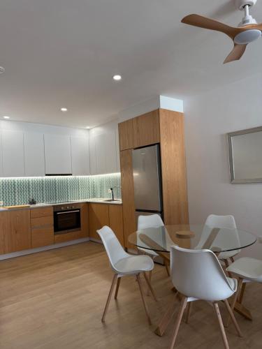 a kitchen with white chairs and a dining room at Radhime Luxury Apartments sleeps 5 in Orikum