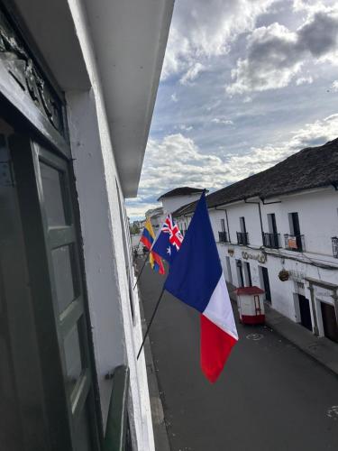 two flags are hanging from a window of a building at Hotel Santa Marta Centro Histórico in Popayan