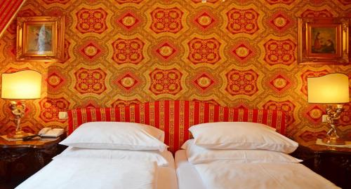 a bedroom with two beds and a wall with a wallpaper at Seehotel Porcia in Pörtschach am Wörthersee