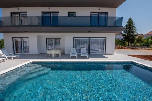 a house with a swimming pool in front of a house at Villa Vibiana Lux Bibinje in Bibinje