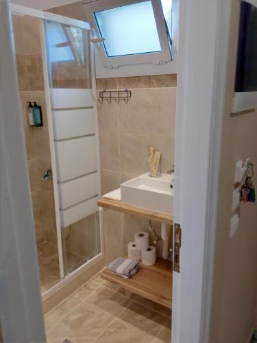 łazienka z umywalką i prysznicem z oknem w obiekcie maria corfu apartments w mieście Mesongi