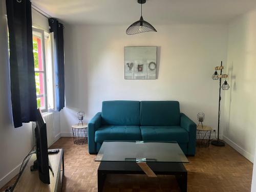 un salon avec un canapé bleu et une table dans l'établissement Appartement T3 Gilaldo, à Anglet