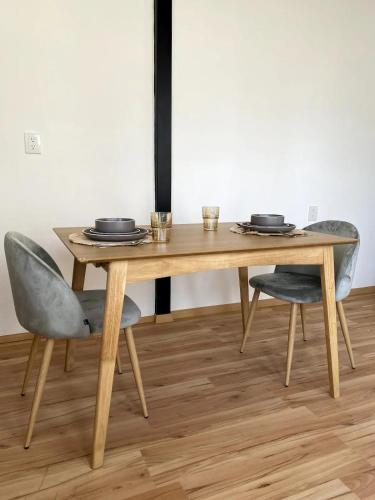 a wooden table and two chairs with plates on it at Your Cozy Corner in Oaxaca with AC in Oaxaca City