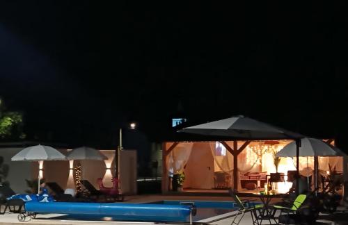 a swimming pool at night with umbrellas and chairs at Apartmani Jozić in Garešnica