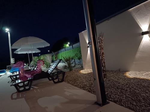 a bench with an umbrella in a yard at night at Apartmani Jozić in Garešnica