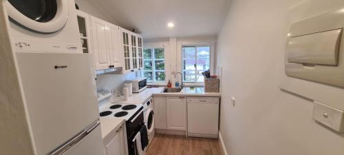 Una cocina con gabinetes blancos y un horno de estufa. en Beachfront Sunset View Apartment - The Coachhouse, en Narrabeen
