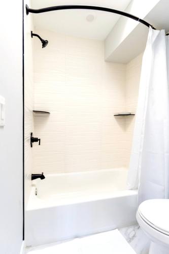 a white bathroom with a tub and a toilet at Elegant Urban Escape - 2 Bedrooms, 1 king Bed and 1 Queen Bed, Gated Private Entrance and Parking in Philadelphia