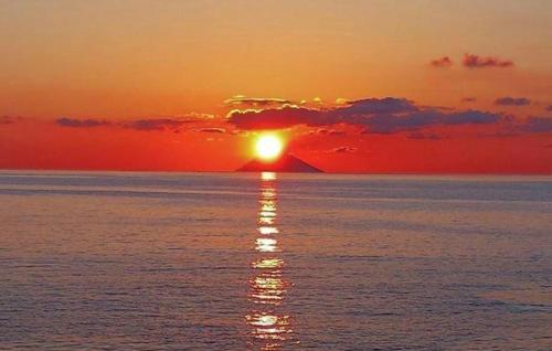 a sunset over the ocean with the sun setting at CasaEolia Golden in Canneto