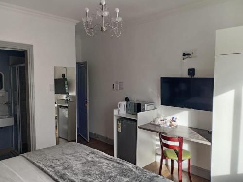 a room with a bed and a kitchen with a table at Camdene Guesthouse in Cape Town