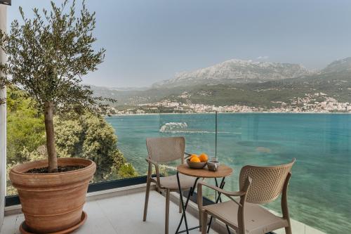 a table and chairs on a balcony with a view of the water at Njivice Coastal Oasis in Njivice
