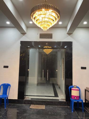 a lobby with two blue chairs and a chandelier at Hotel shree rasal and marriage garden in Maihar