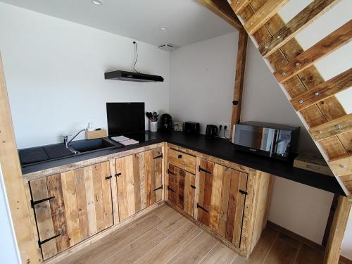 une cuisine avec des armoires en bois et un comptoir noir dans l'établissement La Maison de Pandora, à Maulévrier