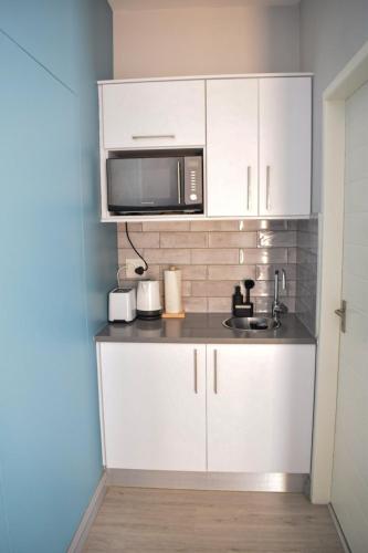 a kitchen with white cabinets and a microwave at Desert Nest I in Swakopmund