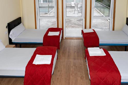two beds and two chairs in a room with windows at Cruce de Caminos Arzúa in Arzúa