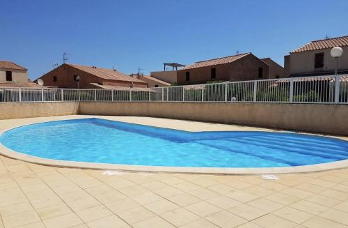 une grande piscine bleue dans une cour avec une clôture dans l'établissement Maison d'exception avec vue sur l'étang, Résidence Lagunes du Soleil, à Gruissan
