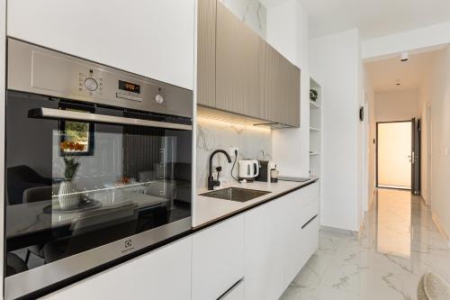 a kitchen with white cabinets and a sink at Njivice Coastal Oasis in Njivice