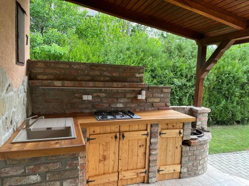 an outdoor kitchen with a sink and a stone wall at Bozsó Villa in Balatonőszöd