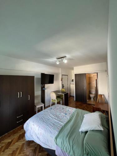 Un dormitorio con una cama grande y un escritorio. en Luminoso y Cálido con Balcón a la calle, en Buenos Aires