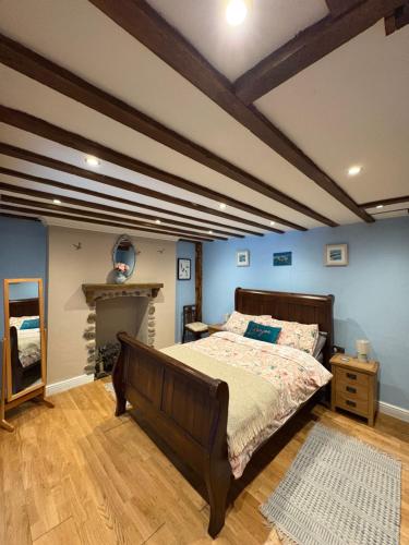a bedroom with a large bed with blue walls at The Old Shop Cottage, Llandudno in Penrhyn Bay