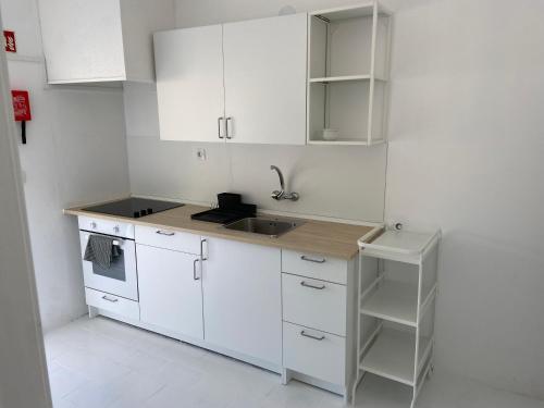 a small kitchen with white cabinets and a sink at Casinha da praia in Costa de Santo André