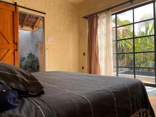 a bedroom with a bed and a large window at Casa Copal Troncones - Bungalows con Alberca Privada in Troncones