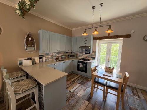 a kitchen with white cabinets and a table with chairs at The Old Shop Cottage, Llandudno in Penrhyn Bay