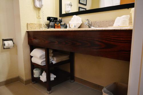 a bathroom with a sink and a pile of towels at Comfort Inn & Suites Covington - Mandeville in Covington