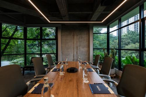 a long wooden table in a room with windows at Faranda Collection Medellin, a Member of Radisson Individuals in Medellín
