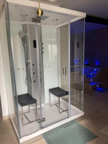 une douche en verre avec deux chaises dans une pièce dans l'établissement L'indiscrete Loveroom, à Saint-Cyr-sur-Loire